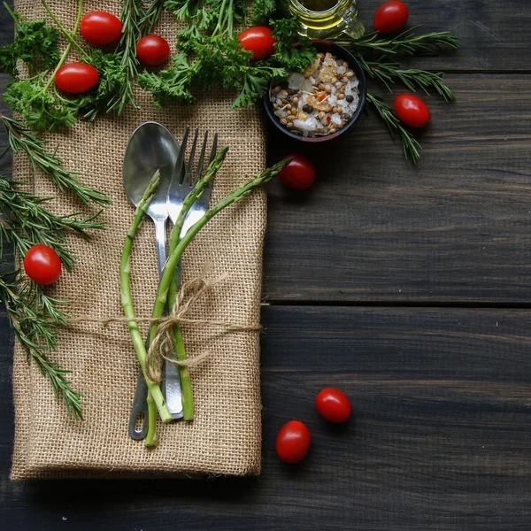 Table with cutlery, herbs, tomatoes and spices — Stock Photo, Image