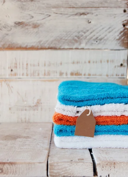 Pila de toallas de colores para la venta con etiqueta de precio sobre fondo de madera, enfoque selectivo — Foto de Stock