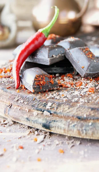 Kousky čokolády s chilli papričkami na dřevěný stůl — Stock fotografie
