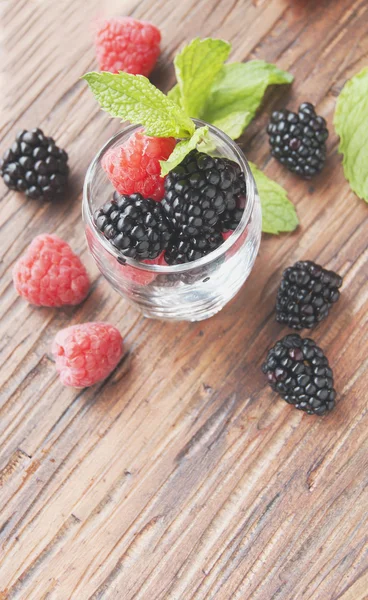 Baies noires et framboises dans une tasse en verre — Photo