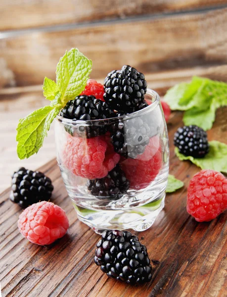 Baies noires et framboises dans une tasse en verre — Photo