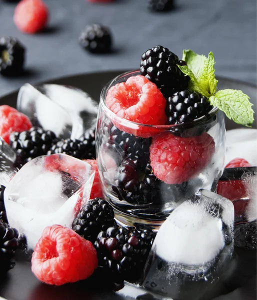 Чорні ягоди і малини в склянці — стокове фото