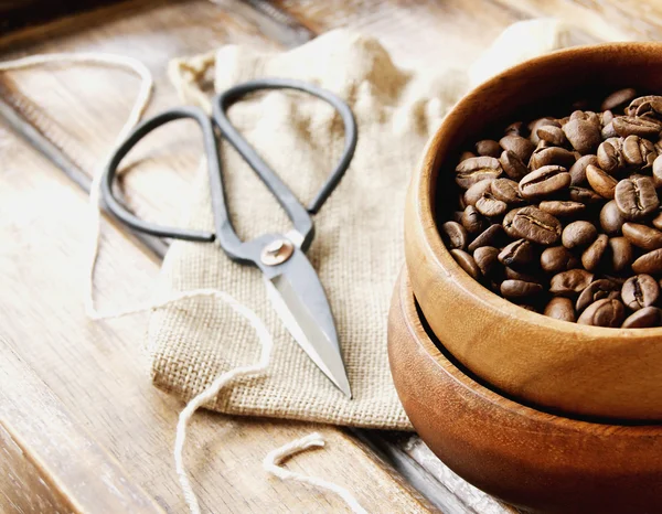 Granos de café en un tazón de madera con bolsa de lona —  Fotos de Stock