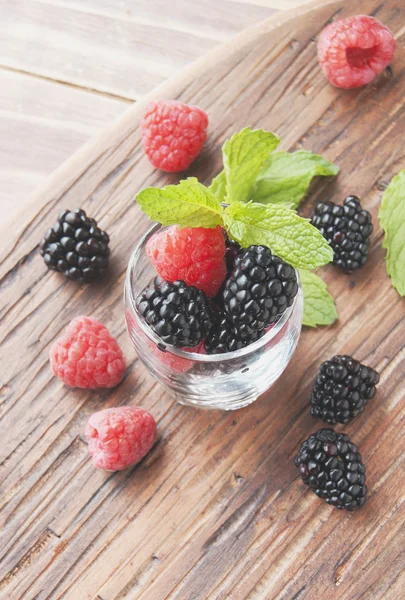 Baies noires et framboises dans une tasse en verre — Photo