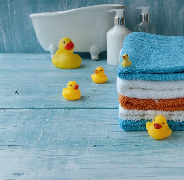 Pila de toallas de colores y pato de baño en la mesa — Foto de Stock