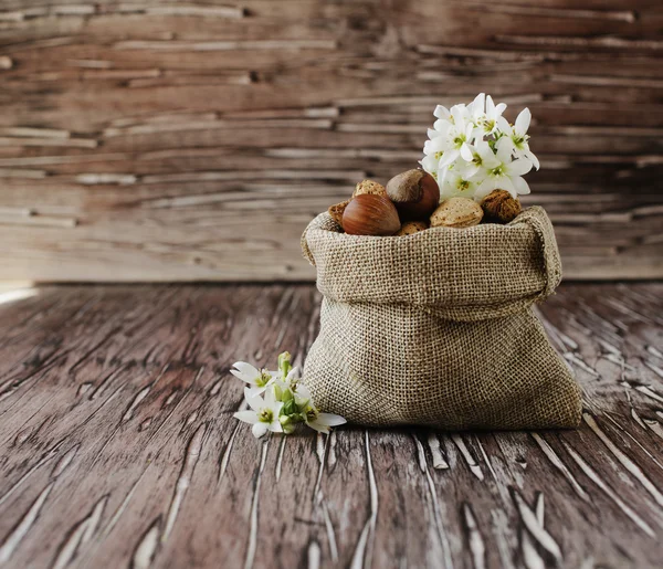 Plátěný pytel s ořechy na dřevěný stůl — Stock fotografie