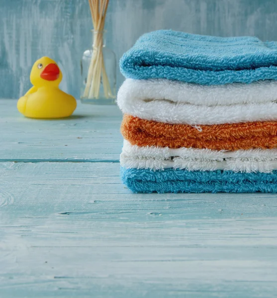 Pila de toallas de colores y pato de baño en la mesa — Foto de Stock