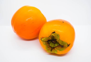 Beyaz arka planda iki olgun portakal hurması (Diospyros kaki).