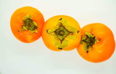 Beyaz arka planda üç olgun portakal hurması (Diospyros kaki)