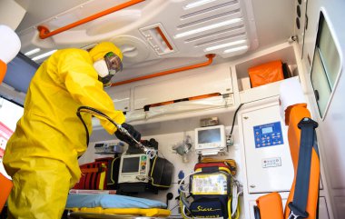 POLTAVA, UKRAINE - 29 Nisan 2021: Koruyucu giysili bir doktor koronavirüsteki ambulansı dezenfekte etti