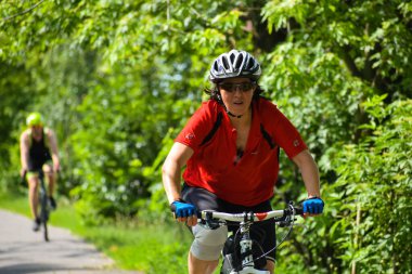 POLTAVA, UKRAINE - 19 Haziran 2021: Bisikletçiler yaz öğleden sonraları triatlon yarışmaları sırasında parkta bisiklet sürerler