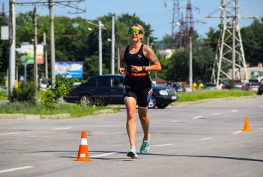 POLTAVA, UKRAINE - 19 Haziran 2021: Triatlon yarışmaları sırasında yaz öğleden sonra koşucular yolda koşar