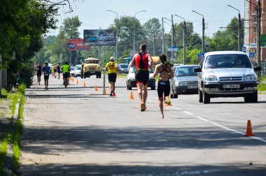 POLTAVA, UKRAINE - 19 Haziran 2021: Triatlon yarışmaları sırasında yaz öğleden sonra koşucular yolda koşar