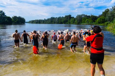 POLTAVA, UKRAINE - 19 Haziran 2021: Yüzücüler triatlon yarışmaları sırasında Vorskla Nehri boyunca yüzerler