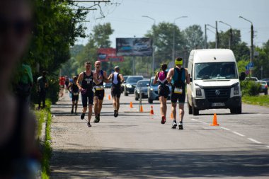 POLTAVA, UKRAINE - 19 Haziran 2021: Triatlon yarışmaları sırasında yaz öğleden sonra koşucular yolda koşar