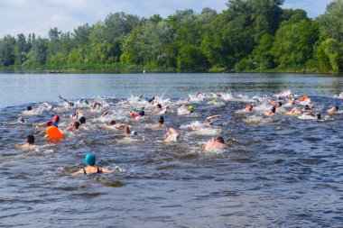 POLTAVA, UKRAINE - 19 Haziran 2021: Yüzücüler triatlon yarışmaları sırasında Vorskla Nehri boyunca yüzerler