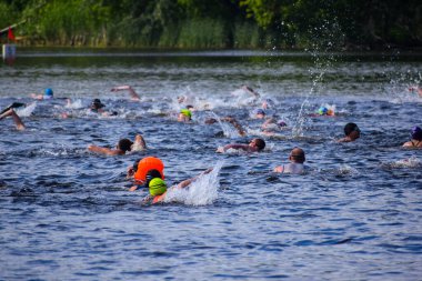 POLTAVA, UKRAINE - 19 Haziran 2021: Yüzücüler triatlon yarışmaları sırasında Vorskla Nehri boyunca yüzerler