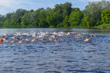 POLTAVA, UKRAINE - 19 Haziran 2021: Yüzücüler triatlon yarışmaları sırasında Vorskla Nehri boyunca yüzerler