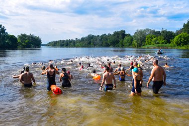 POLTAVA, UKRAINE - 19 Haziran 2021: Yüzücüler triatlon yarışmaları sırasında Vorskla Nehri boyunca yüzerler