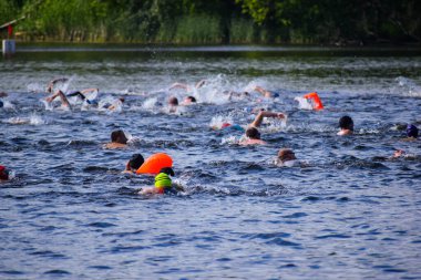 POLTAVA, UKRAINE - 19 Haziran 2021: Yüzücüler triatlon yarışmaları sırasında Vorskla Nehri boyunca yüzerler
