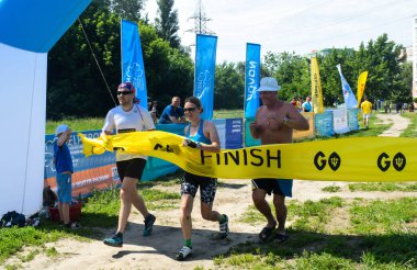 POLTAVA, UKRAINE - 19 Haziran 2021: Sporcu triatlon yarışması sırasında bitiş çizgisini geçiyor
