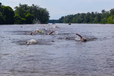 POLTAVA, UKRAINE - 19 Haziran 2021: Yüzücüler triatlon yarışmaları sırasında Vorskla Nehri boyunca yüzerler