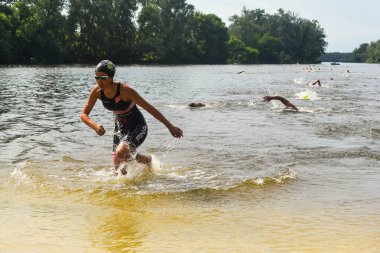 POLTAVA, UKRAINE - 19 Haziran 2021: Yüzücüler triatlon yarışmaları sırasında Vorskla Nehri boyunca yüzerler