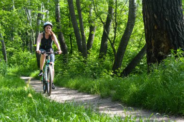 POLTAVA, UKRAINE - 19 Haziran 2021: Bisikletçiler yaz öğleden sonraları triatlon yarışmaları sırasında parkta bisiklet sürerler
