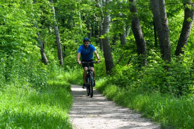 POLTAVA, UKRAINE - 19 Haziran 2021: Bisikletçiler yaz öğleden sonraları triatlon yarışmaları sırasında parkta bisiklet sürerler