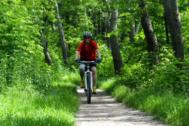 POLTAVA, UKRAINE - 19 Haziran 2021: Bisikletçiler yaz öğleden sonraları triatlon yarışmaları sırasında parkta bisiklet sürerler