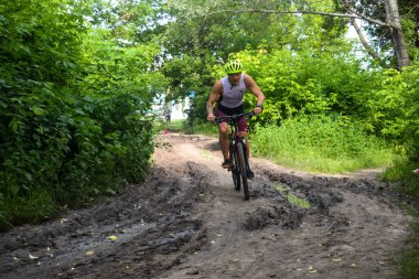 POLTAVA, UKRAINE - 19 Haziran 2021: Bisikletçiler yaz öğleden sonraları triatlon yarışmaları sırasında parkta bisiklet sürerler