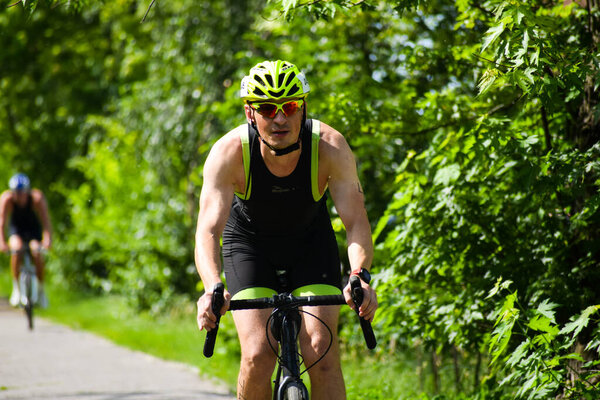 ПОЛТАВА, УКРАИНА - 19 ИЮНЯ, 2021: Велогонщики катаются на велосипедах в парке летом днем во время соревнований по триатлону