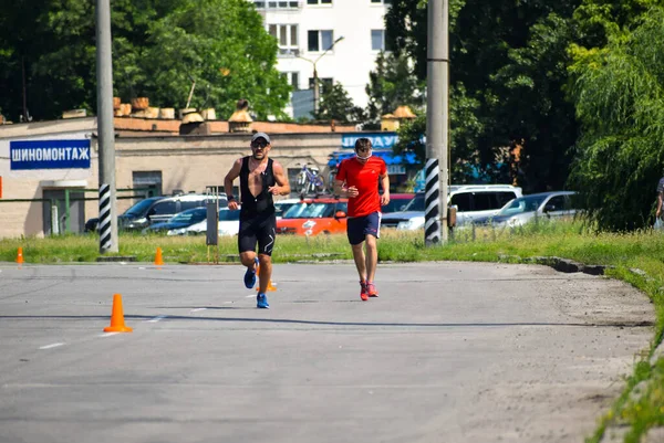 POLTAVA, UKRAINE - 19 Haziran 2021: Triatlon yarışmaları sırasında yaz öğleden sonra koşucular yolda koşar
