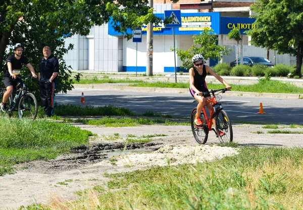 POLTAVA, UKRAINE - 19 Haziran 2021: Bisikletçiler yaz öğleden sonraları triatlon yarışmaları sırasında parkta bisiklet sürerler