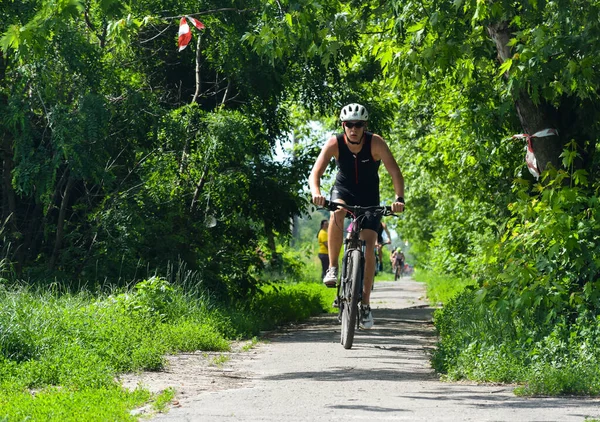 POLTAVA, UKRAINE - 19 Haziran 2021: Bisikletçiler yaz öğleden sonraları triatlon yarışmaları sırasında parkta bisiklet sürerler