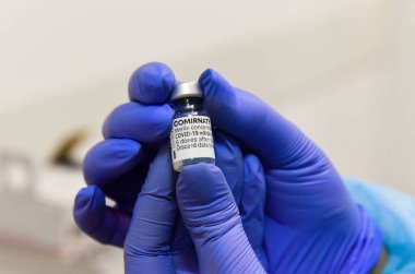 Poltava, Ukraine - 21 July, 2021: Ampoule of the vaccine from COVID-19 ComirnatyPfizer-BioNTech in the hands of a doctor