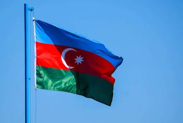 Azerbaycan bayrağı üç eşit yatay şeritten oluşur - mavi, kırmızı ve yeşil, bayrağın ortasında sekiz köşeli yıldızlı hilal bir ay tasvir eder.