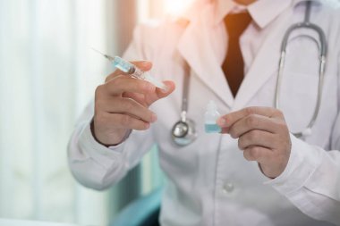 Maskeli doktor şırıngayla aşı oluyor. 