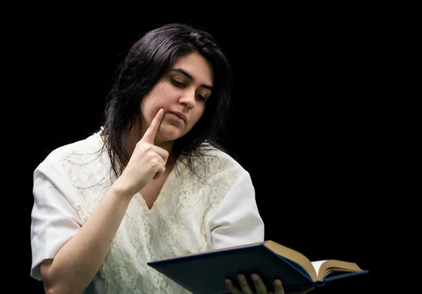 Latina teen in white holding a book on black background — Stock Photo, Image
