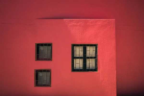 A red wall with black windows, Two decorative black windows on an old red stucco wall