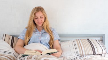 güzel kız yatakta yatarken kitap okuma