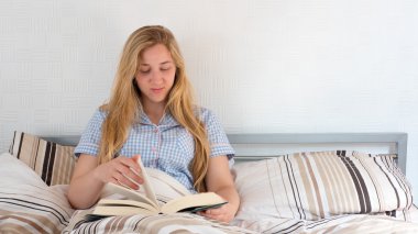 güzel kız yatakta yatarken kitap okuma