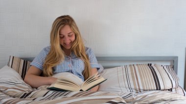 güzel kız yatakta yatarken kitap okuma