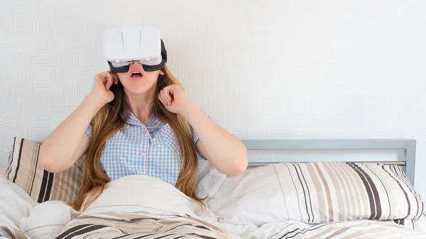 Mulher bonita usando fone de ouvido VR na cama — Fotografia de Stock
