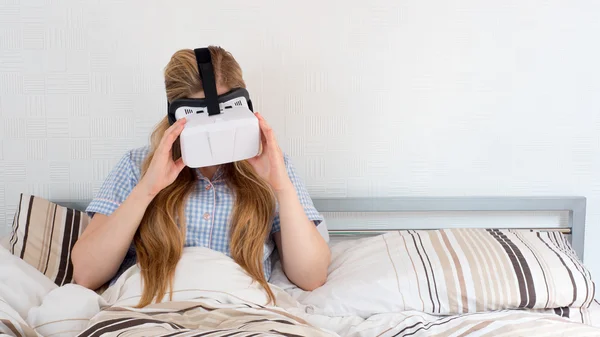 Красива жінка використовує гарнітуру VR в ліжку — стокове фото