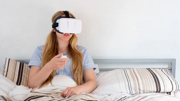 Mulher bonita usando fone de ouvido VR na cama — Fotografia de Stock