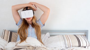 Güzel kadın yatakta VR kulaklık kullanarak