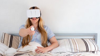 Güzel kadın yatakta VR kulaklık kullanarak