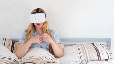 Güzel kadın yatakta VR kulaklık kullanarak