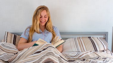 güzel kız yatakta yatarken kitap okuma